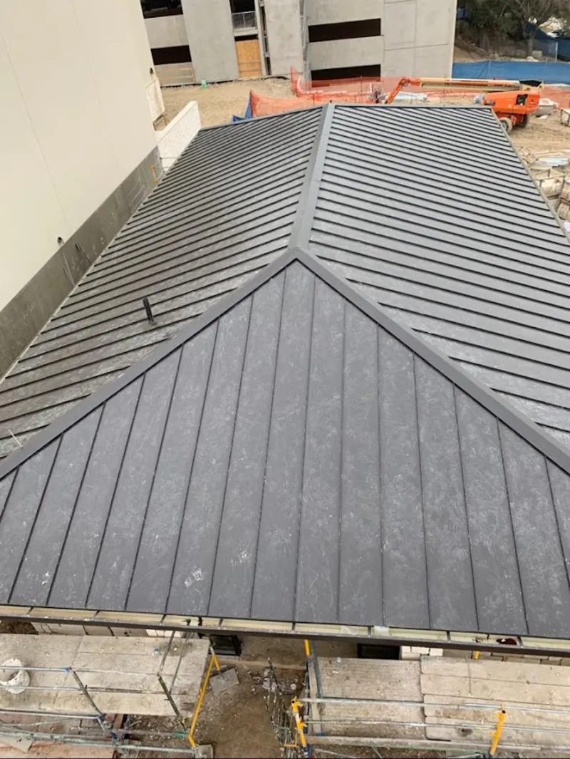 Commercial metal roof construction with crane equipment in West Slope